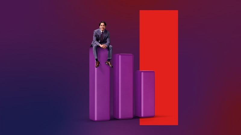 A man in a suit perched atop a bar graph emerging from a red door