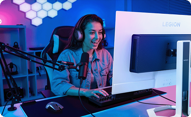 A lifestyle photo features a woman smiling as she using the Legion Pro monitor, which enhances the gaming experience