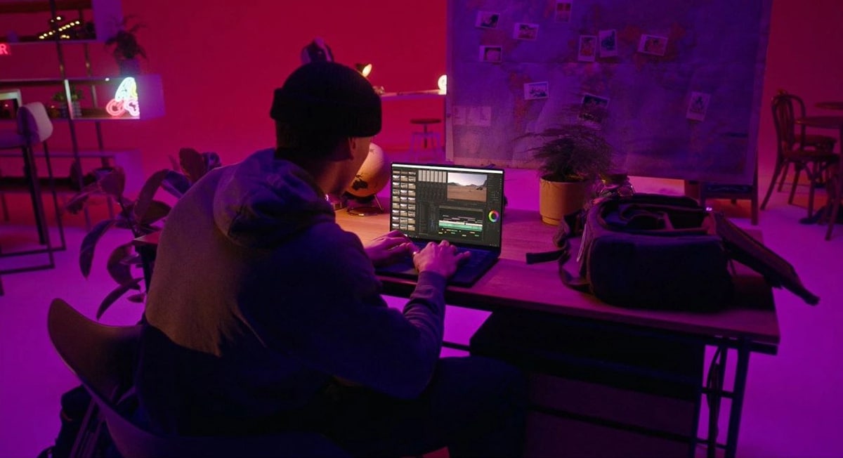 Группа молодых людей общается вокруг лежащего на столе ноутбука Lenovo Yoga, помещение освещено мрачным красным цветом