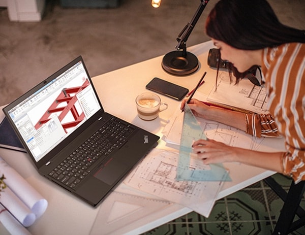 An architect working on drawings, with a ThinkPad T15p Gen 3 (15" Intel) mobile workstation opened on a desk