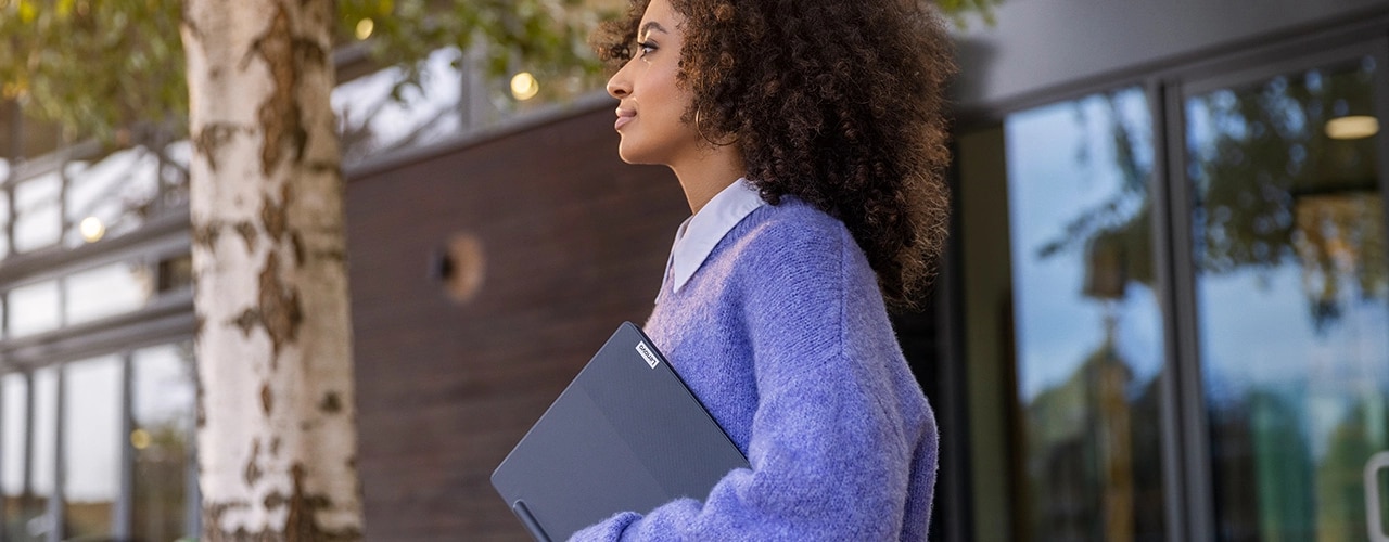 Person holding Lenovo Smart Paper E-Ink reader, with Lenovo Smart Pen, under arm while walking