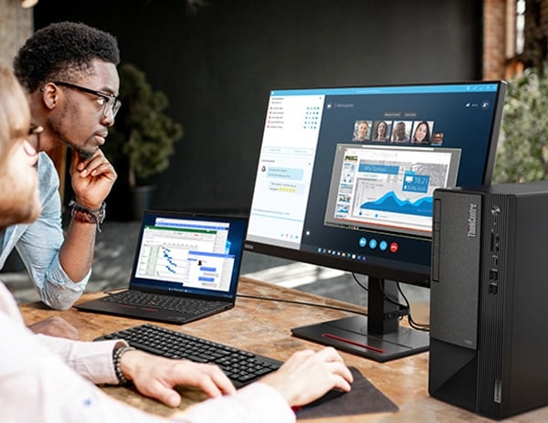 Two people at a desk with a ThinkCentre Neo 50t Gen 4 (Intel) business tower with optional monitor and Smart Cable
