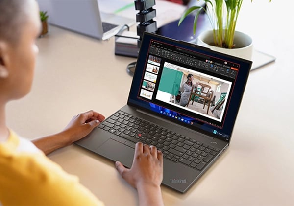 Una persona en una mesa trabajando con una presentación en un portátil Lenovo ThinkPad E16 [40,64 cm (16