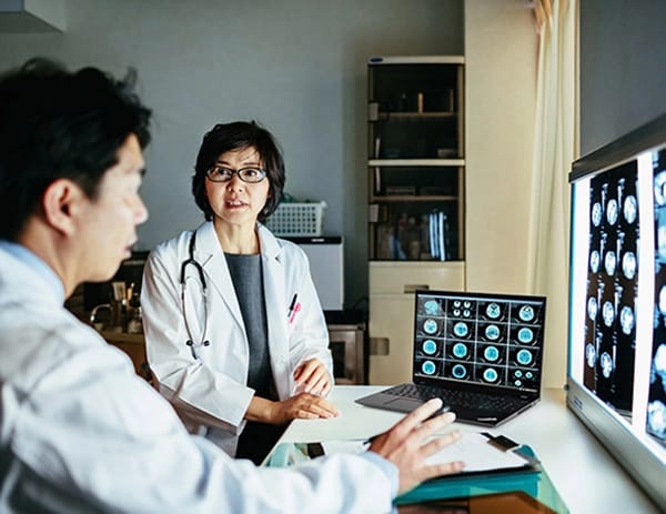 Two doctors looking at medical scan images on large screens, with a Lenovo ThinkPad P16s Gen 2 (16″ Intel) laptop, opened on desk